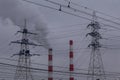 Industrial pipes with smoke and electric powerlines on grey sky with smog background, air pollution concept