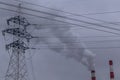 Industrial pipes with smoke and electric powerlines on grey sky with smog background, air pollution, copy space