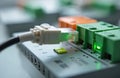 Industrial PLC controller system closeup. Ethernet cable plugs into modular unit port, displaying bright green LED lights. Royalty Free Stock Photo