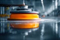 Industrial polishing machine with a bright orange buffer working on a reflective metal surface in a spacious and well-lit Royalty Free Stock Photo