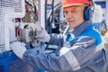 Industrial portrait electrician worker man at factory in hard hat and headphones performs start of equipment machine