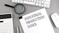 INDUSTRIAL PRODUCTION INDEX written on paper with office tools and keyboard on the grey background