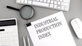 INDUSTRIAL PRODUCTION INDEX written on paper with office tools and keyboard on the grey background Royalty Free Stock Photo