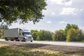 Industrial professional big rig semi truck tractor with dry van semi trailer running on the divided highway road