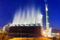 Industrial refinery at night with cooling water smoke