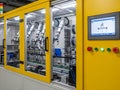 Industrial robot arm operating inside a yellow automated manufacturing machine with control panel Royalty Free Stock Photo