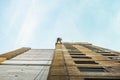 Industrial rope access worker hanging from the building while painting the exterior facade wall. Industrial alpinism concept image