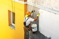 Industrial rope access worker hanging from the building while painting the exterior facade wall. Industrial alpinism concept image