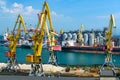 Industrial seaport infrastructure, sea, cranes and dry cargo ship, grain silo, bulk carrier vessel and grain storage elevators,