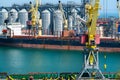 Industrial seaport infrastructure, sea, cranes and dry cargo ship, grain silo, bulk carrier vessel and grain storage elevators,