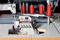 Industrial sewing machine with red spools of thread on a dark workshop background Royalty Free Stock Photo