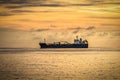 Industrial ship on anchor in the open sea at sunrise