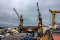 Industrial ship repair yard with floating dock, cranes hoist vessels for maintenance. Maritime engineering, dockyard