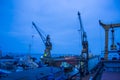 Industrial shipyard at dusk, floating dry dock with ship under repair, cranes standby. Maritime vessel maintenance Royalty Free Stock Photo