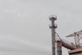 Industrial site with pipes and smokestacks against a gray sky, ample copy space