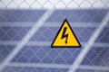 Industrial solar power farm station on background selective focus on yellow triangular high voltage warning sign. Royalty Free Stock Photo