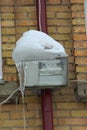 Industrial spotlight lamp hanging on a brick wall of a building covered with snow and ice with icicles in winter in Russia Royalty Free Stock Photo