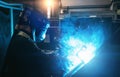 Industrial steel welder in process of work in metal factory. Sparks and smoke fly from welding Royalty Free Stock Photo