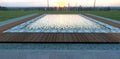 Industrial sunset. View from the porch of a country house. The rays of the setting sun are reflected in the pool, surrounded by