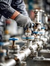 Industrial technician wearing protective gloves adjusting metal valve on complex pipeline system in a manufacturing or processing Royalty Free Stock Photo