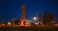 Industrial territory with water tower and full moon above.