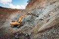 Industrial track type excavator digging and loading ore in a dumper truck at a quarry Royalty Free Stock Photo