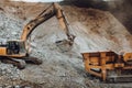 Industrial track type excavator digging and loading rock crusher