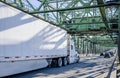 Industrial transportation big rig semi truck carry cargo in dry van semi trailer with aerodynamic skirt running on the long truss