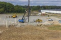 Industrial view of construction site with machinery and pile driving machine for driving piles into ground.