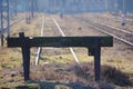 Industrial view of dead end for the train at the old station, black wooden fence. The rails go far beyond the horizon on a Sunny