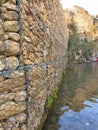 An industrial wall of cobble stone on the edge of a pool of water