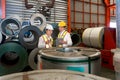 Industrial warehouse scene featuring two safety-conscious men inspecting steel sheet roll stack, imbued with the raw essence of Royalty Free Stock Photo