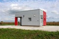 Industrial water pumping station inside concrete structure with metal walls surrounded with asphalt and grass with cornfield and