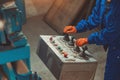 Industrial worker in blue uniform, orange gloves operating control panel with joysticks and buttons Royalty Free Stock Photo