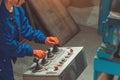 Industrial worker in blue uniform, orange gloves operating control panel with joysticks and buttons Royalty Free Stock Photo