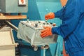Industrial worker in blue uniform, orange gloves operating control panel with joysticks and buttons Royalty Free Stock Photo