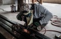 Industrial Worker at the factory welding closeup. Electric wheel grinding on steel structure in factory. Royalty Free Stock Photo