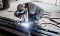 Industrial Worker at the factory welding closeup. Electric wheel grinding on steel structure in factory. Royalty Free Stock Photo