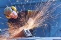 Worker grinding weld seam with grinder machine and sparks