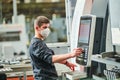 Industrial worker operating cnc machine in protective mask at metal machining industry Royalty Free Stock Photo