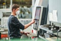 Industrial worker operating cnc machine in protective mask at metal machining industry Royalty Free Stock Photo