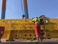 Industrial worker with safety boots and helmet in action. Deep blue sky and yellow iron construction