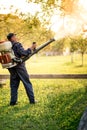 Industrial worker using machine for organic pesticide distribution in fruit orchard Royalty Free Stock Photo