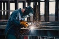 Industrial worker welding steel structure at construction site, sparks flying, intense labor Royalty Free Stock Photo