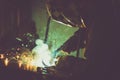 Industrial worker welding on work table, producing smoke, sparks and reflections Royalty Free Stock Photo