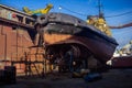 Industrial workers repair fishing boat in dry dock. Maintenance of marine vessel hull, welding, painting under blue sky Royalty Free Stock Photo