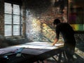 Industrial Workspace: Architect Revising Blueprint in Sunlight-Drenched Studio Royalty Free Stock Photo