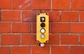 Industrial yellow switch box with power on and off switches buttons and key lock installed outdoors on a red brick wall from wareh Royalty Free Stock Photo