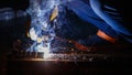 Industry safety working concept. Welder holding a steel welding machine weld piece of metal in a factory at night time. Nice bokeh Royalty Free Stock Photo