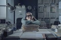 Inefficient office worker leaning on a pile of paperwork